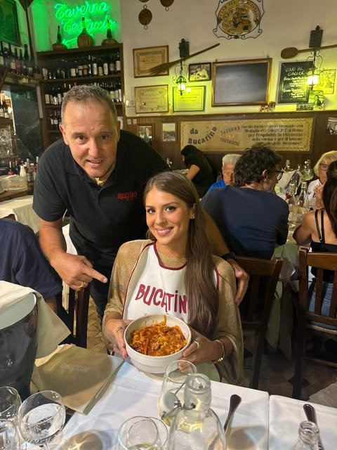 Un’ospite con il bavaglino di Bucatino, un piatto di pasta e le persone della trattoria