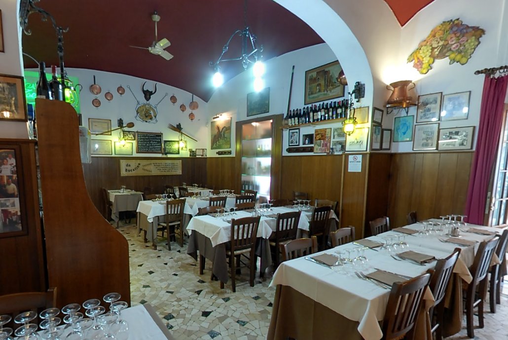La sala con archi rossi, fotografie alle pareti e bottiglie di vino
