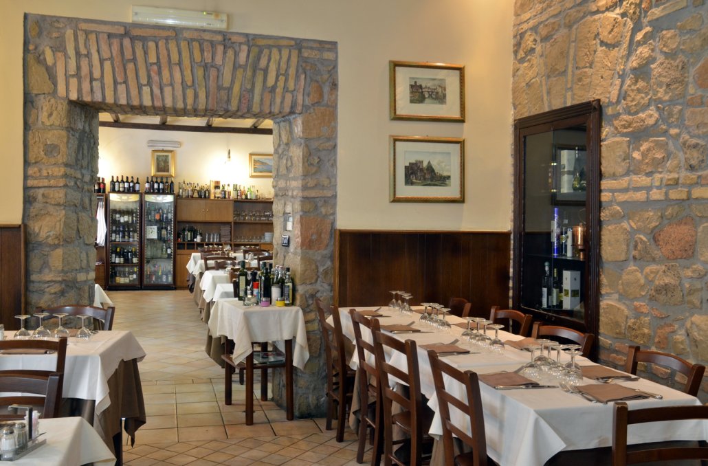 La sala chiara con tovaglie bianche, sedie in legno e arco in pietra